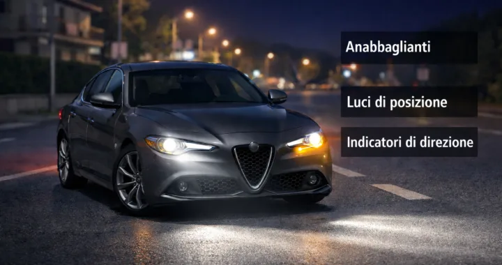 Automobile di notte con anabbaglianti accesi e schema delle luci obbligatorie secondo il Codice della Strada italiano